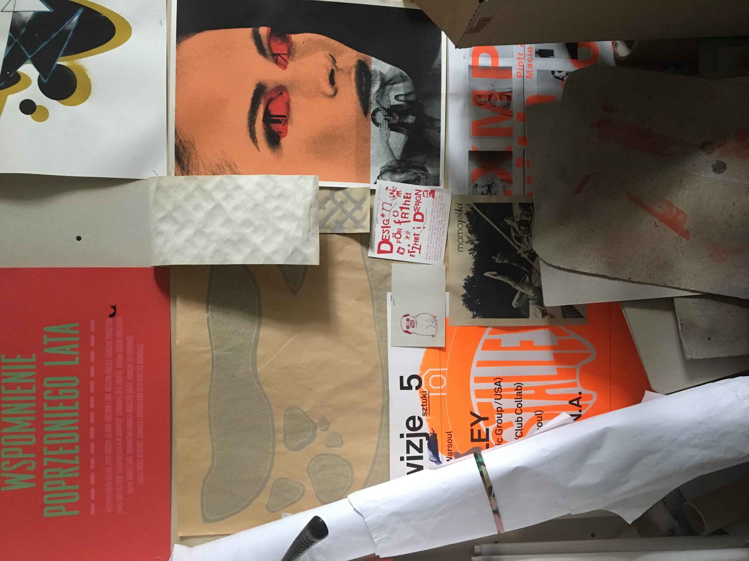 A corner of the studio wall, layered with posters, prints and stickers.
