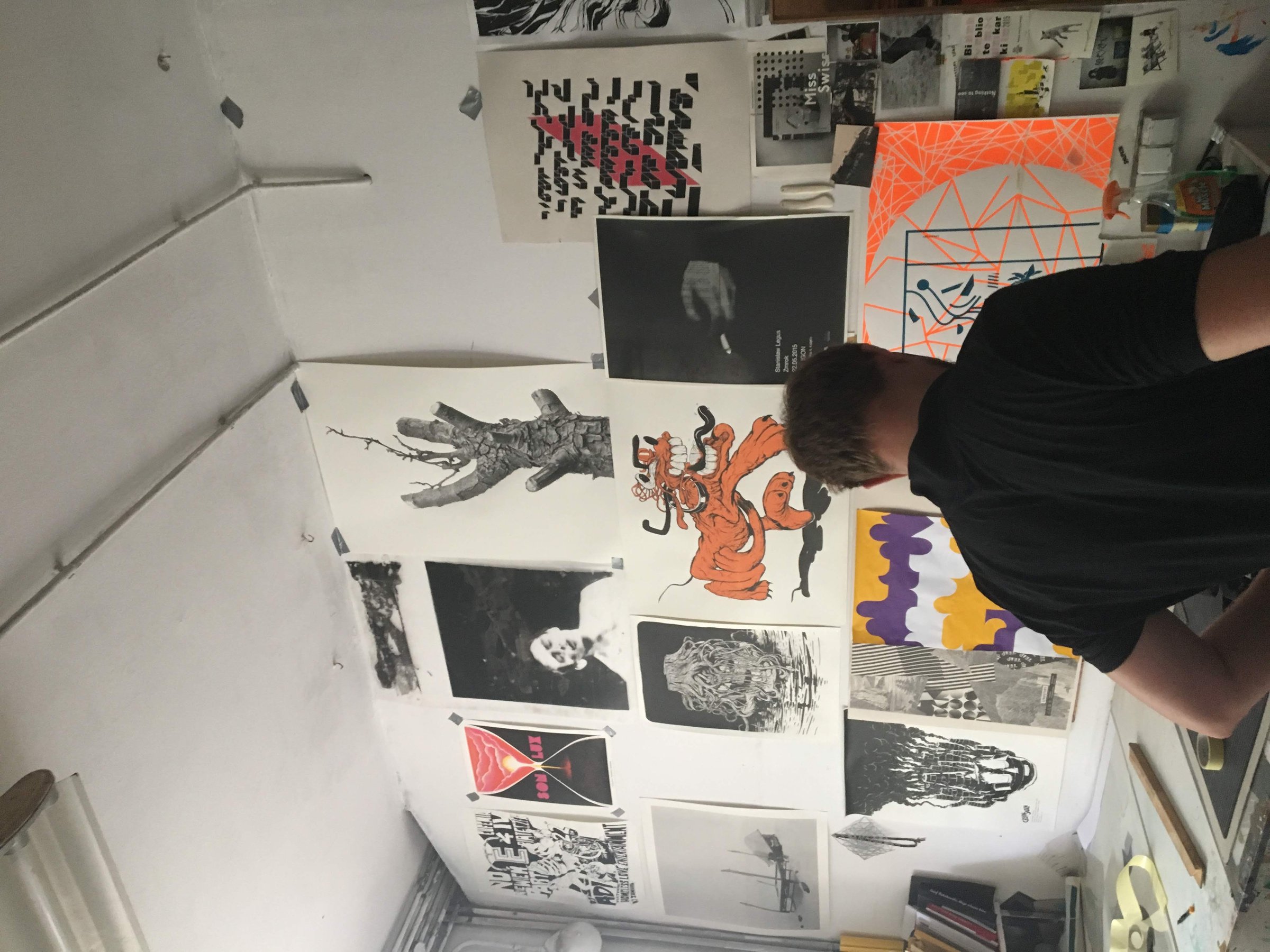 Working at the bench under a wall covered in screen printed posters.